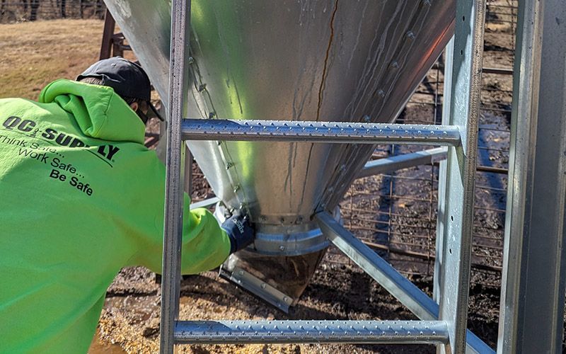 man wearing a qc supply jacket repairing an object on a farm