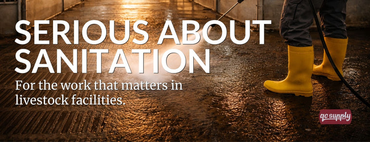 Worker pressure washing a livestock barn floor during sanitation process
